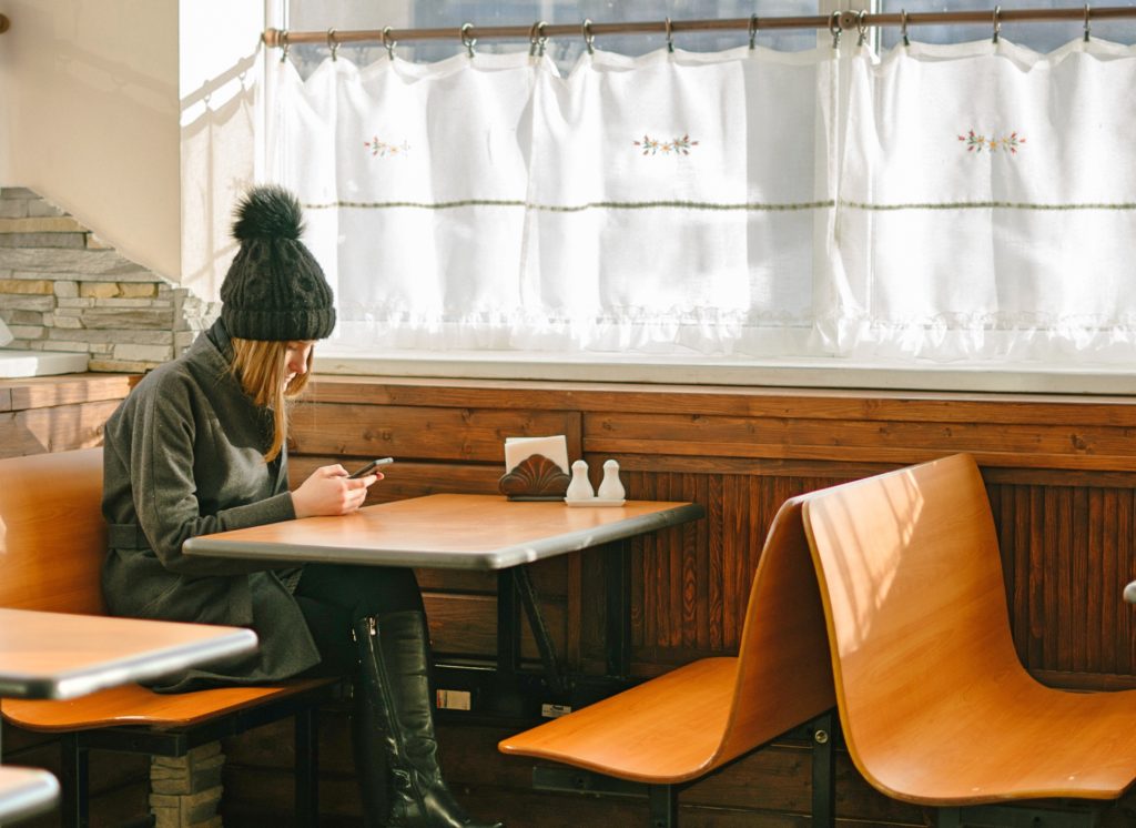 Relocating Tips - Girl looking at her phone at a diner.